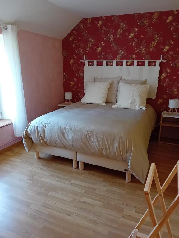 a bedroom with a large bed with a red wall at Les Castelblotines in Châteaubleau