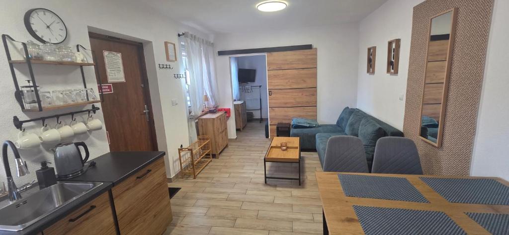 a kitchen and living room with a couch and a clock at Apartament Nova Kamienica 1 in Łagów
