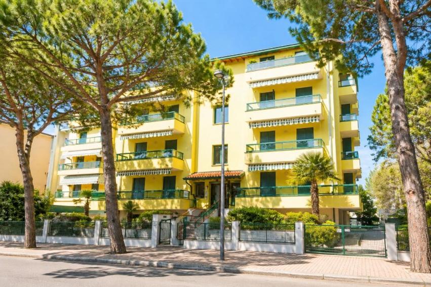 a yellow building with trees in front of it at Residence Pineta - Agenzia Cocal in Caorle