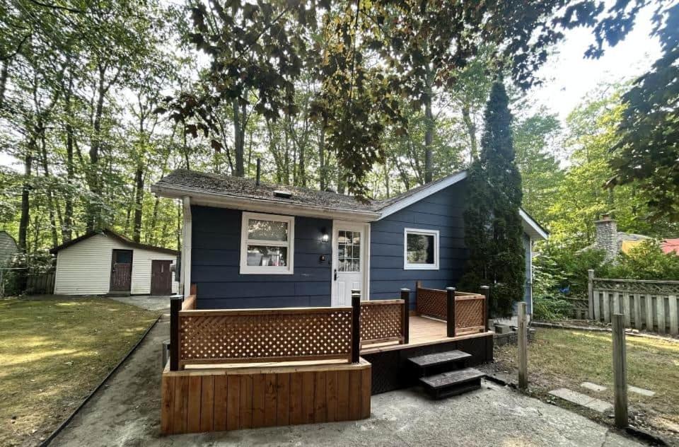 a blue tiny house with a porch and a bench at Lazy Daze in Wasaga Beach in Wasaga Beach