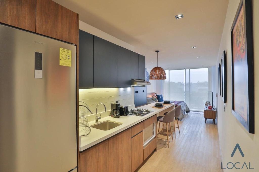 A long studio perspective highlights the kitchen sink, island seating and bright end window.