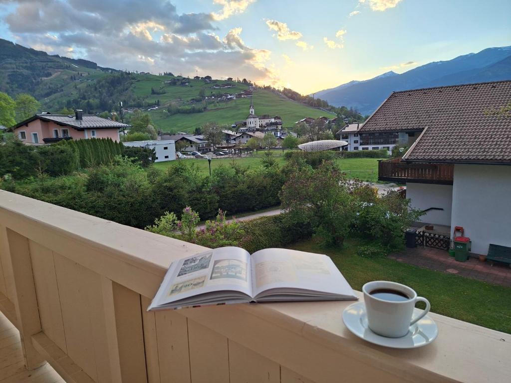 a book and a cup of coffee sitting on a balcony at Lovely Rita Studio, modern Studio - balcony and mountain view - center Kaprun in Kaprun