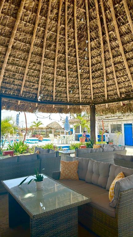 a patio with a couch and a table and a straw roof at Pacha beach club in Barra de Tuxpan
