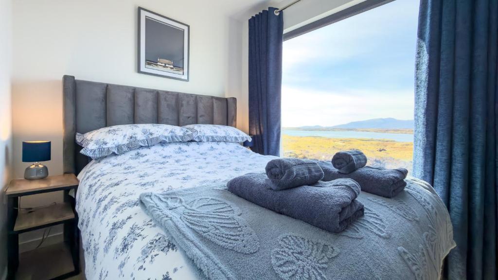 a bedroom with a bed with towels and a window at Bothan By The Bay, Benbecula in Grimsay