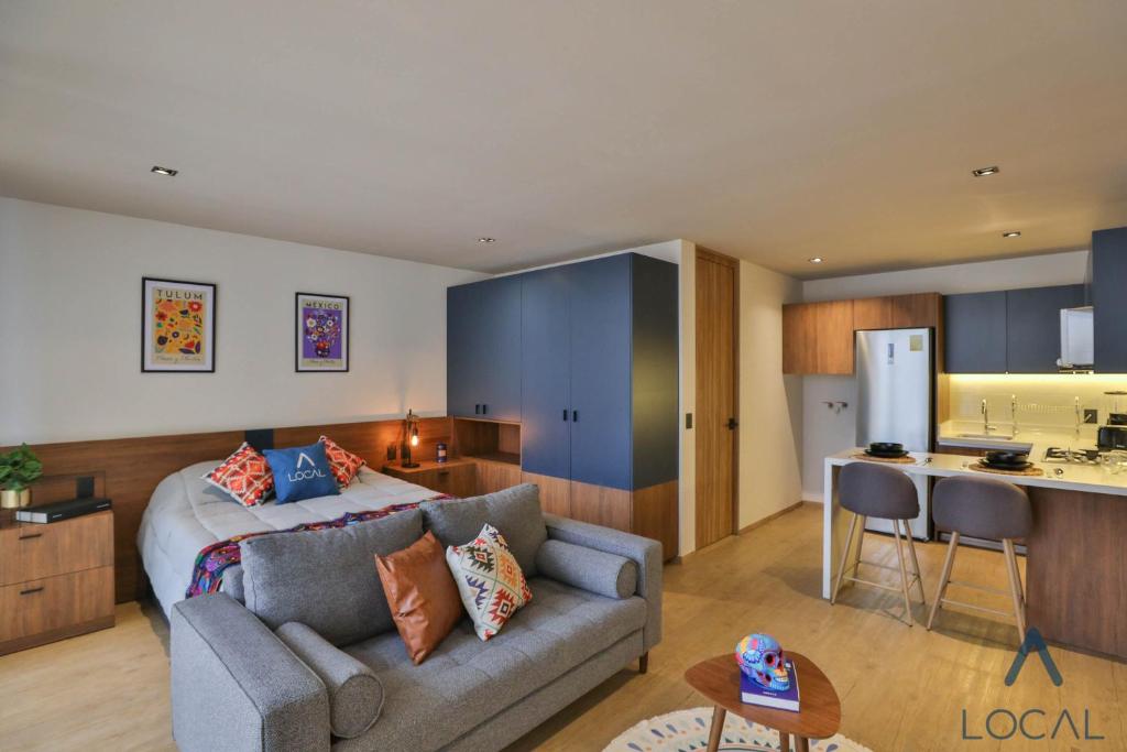 A sofa-led studio view shows the sleeping area, kitchen island and built-in storage together.