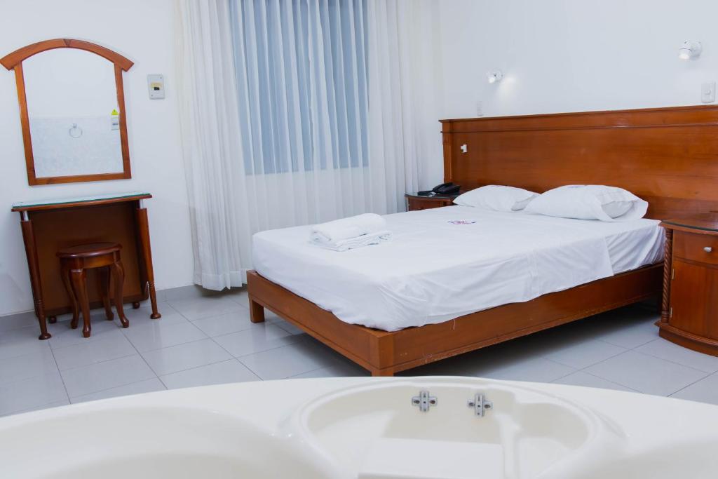 a bedroom with a bed and a tub and a sink at Zentra San José Hotel & Cowork in Chiclayo