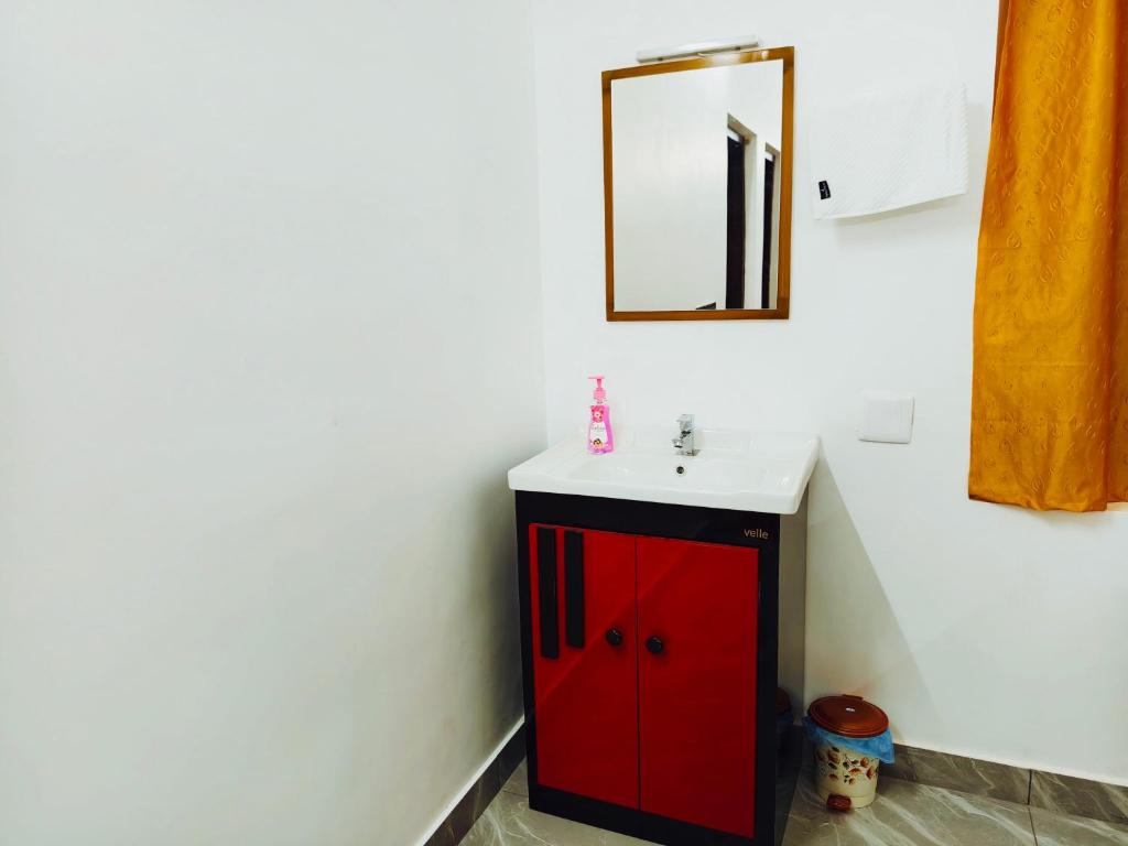 a bathroom with a red cabinet and a mirror at Nilavu villas in Alleppey