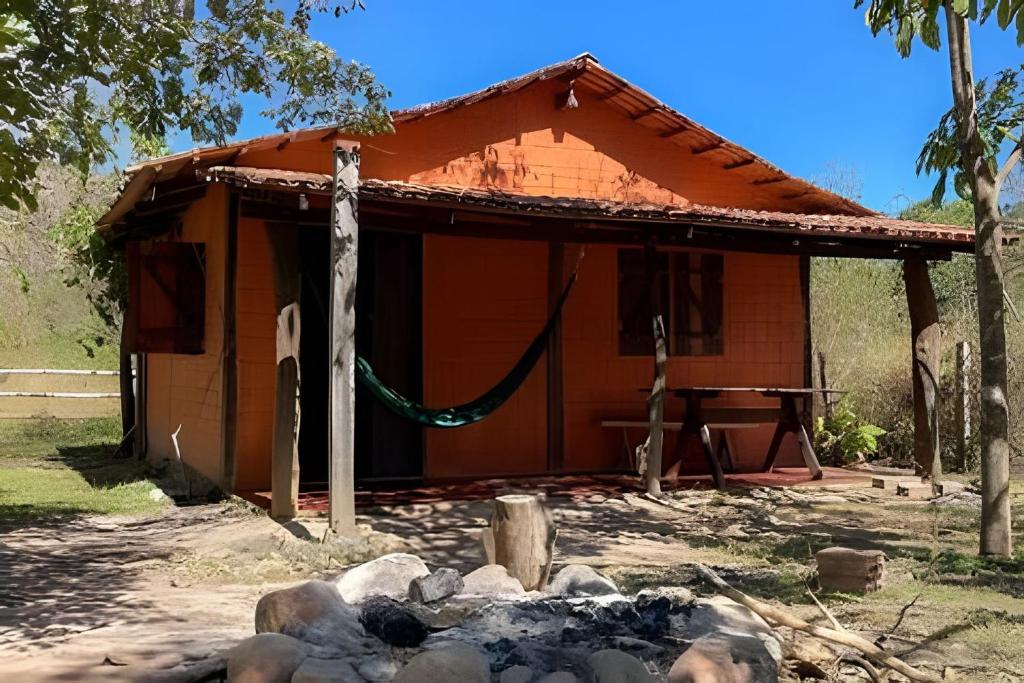 a small house with a hammock in front of it at Chalé Prainha com Cozinha - Valle das Pedras in Sao Jorge