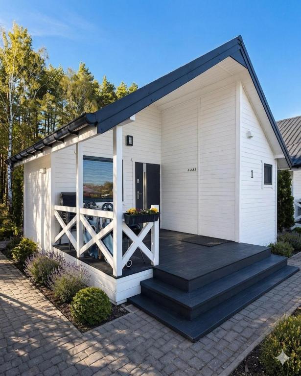 a white house with a porch with a wooden deck at Biały Koral in Rusinowo