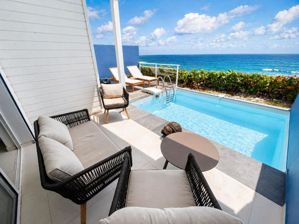 a patio with a table and chairs and a swimming pool at Villa Ar Mor - Oceanfront pool & Saint-Barth view Oyster pond in Saint Martin