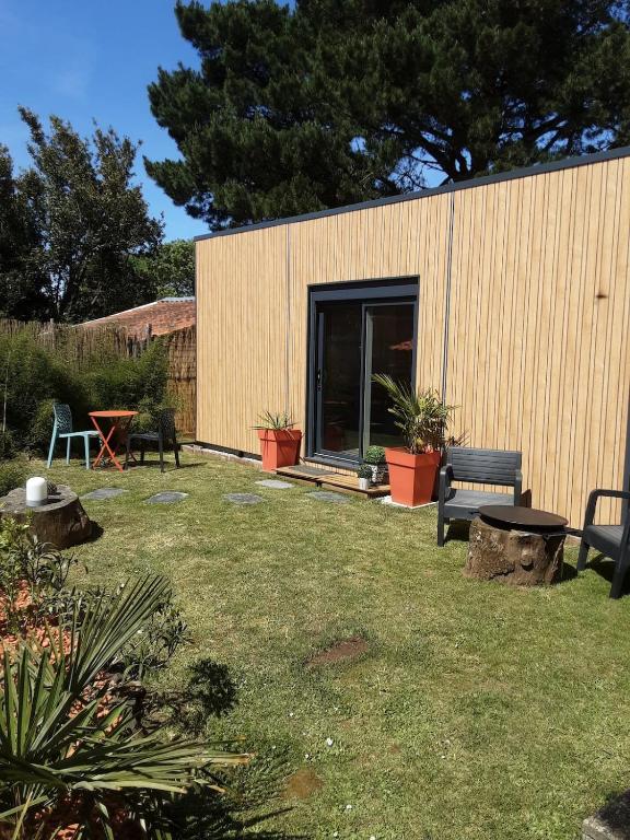 a backyard with a building with a bench and plants at Studio de jardin dans son écrin de verdure in Saint-Lumine-de-Coutais