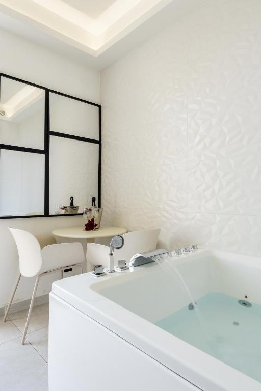 a white bathroom with a tub and a table at Suite luxe jacuzzi - CANNES SUQUET in Cannes