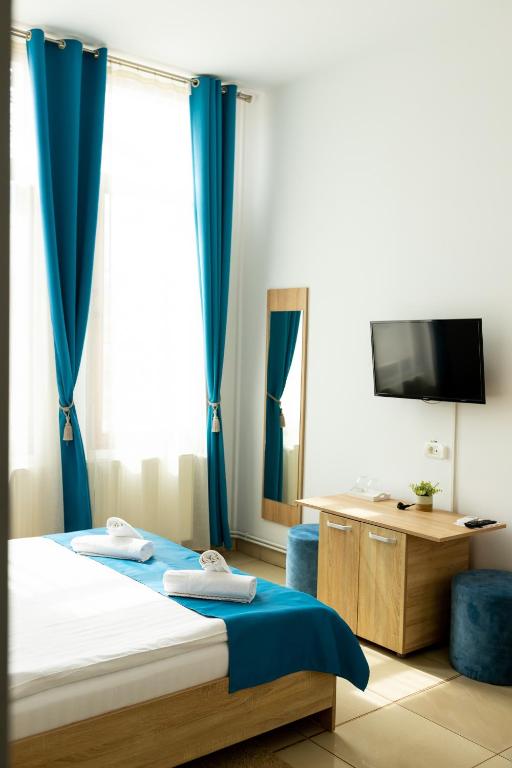 a bedroom with a bed with blue curtains and a desk at MARCONI GUESTHOUSE in Hunedoara