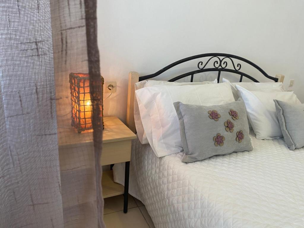 a bed with white pillows and a table with a lamp at Ravanos Apartment in Loutraki