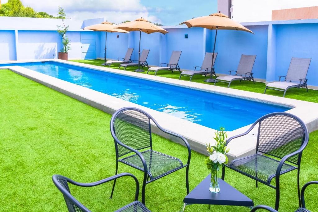 a pool with chairs and umbrellas next to a building at NH Puebla FINSA in Puebla