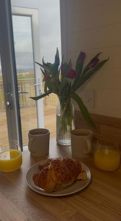 a table with a plate of food and a vase with flowers at Hillhouse Coastal Escapes - PODs in Donegal
