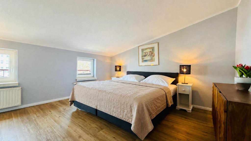 a bedroom with a large bed and two windows at CBlue "Apartmenthaus Chrischanshof" in Warnemünde