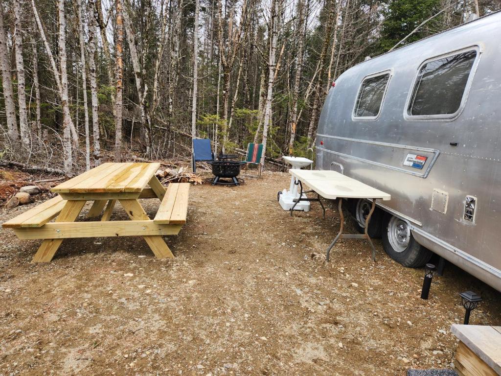 a picnic table and a trailer in the woods at Orange Lake Airstream in Whiting