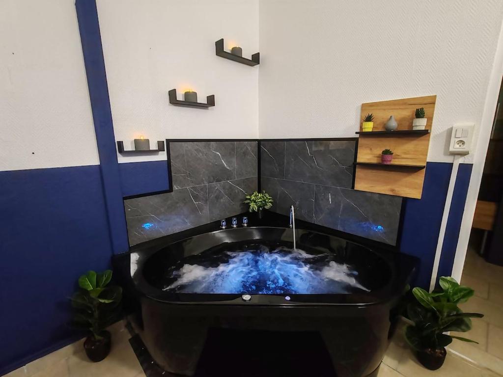 ein Badezimmer mit einer schwarzen Badewanne mit Wolkenmuster in der Unterkunft Le Maley in Dunkerque