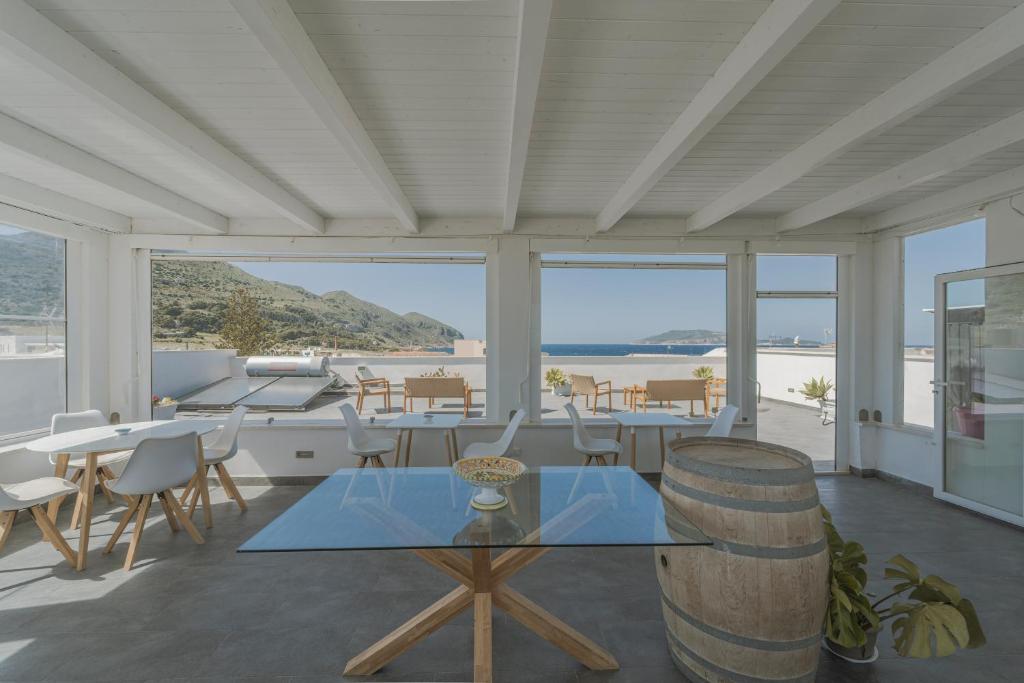 a room with tables and chairs and a view of the ocean at Ponente & Maestro Rooms in Favignana
