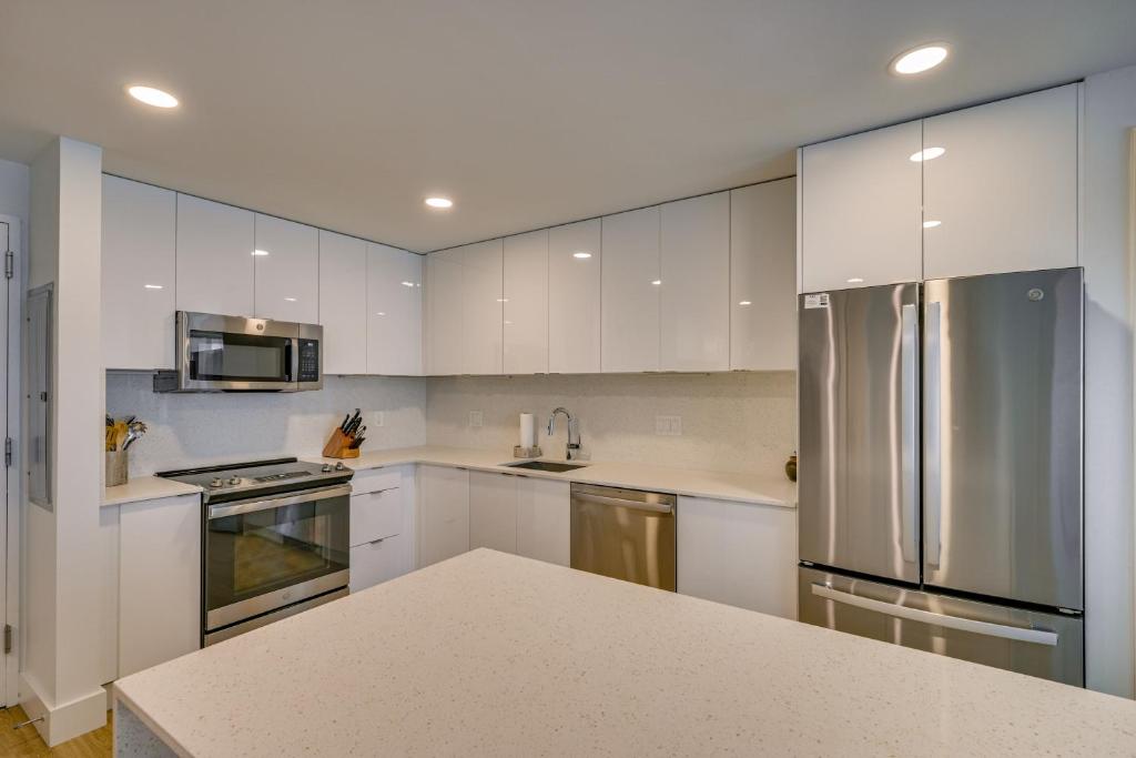 a kitchen with white cabinets and a stainless steel refrigerator at Walk to MIT & T Stop! Kendall Square Extended Base in Cambridge