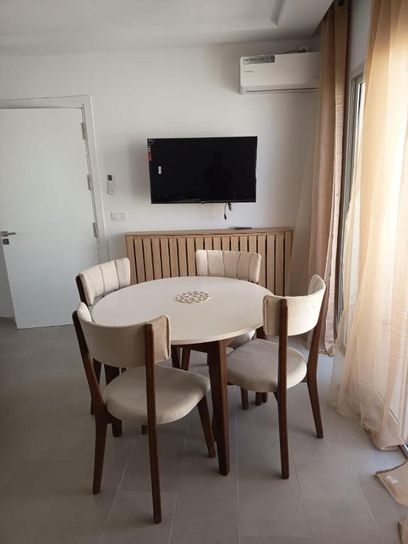 a dining room with a table and chairs and a tv at La tulipe d'Hammamet in Hammamet