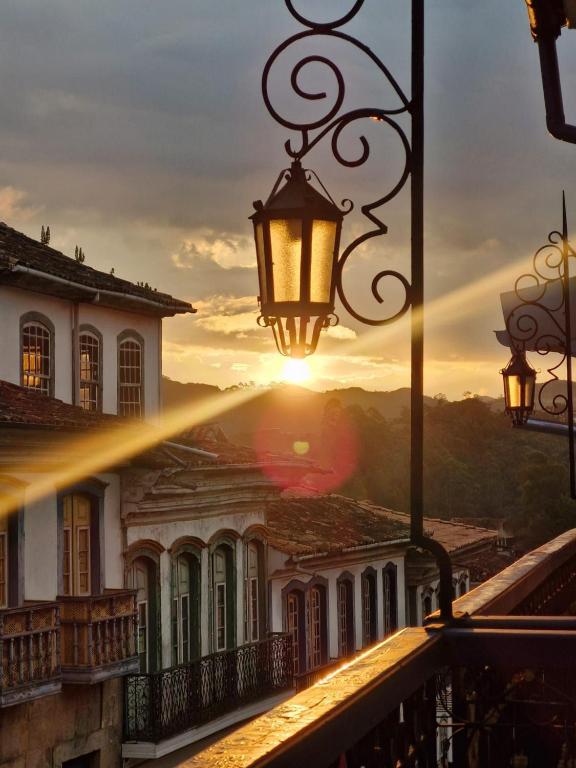 a beam of sunlight shines on a building with a street light at Pousada Memórias de Minas in Ouro Preto