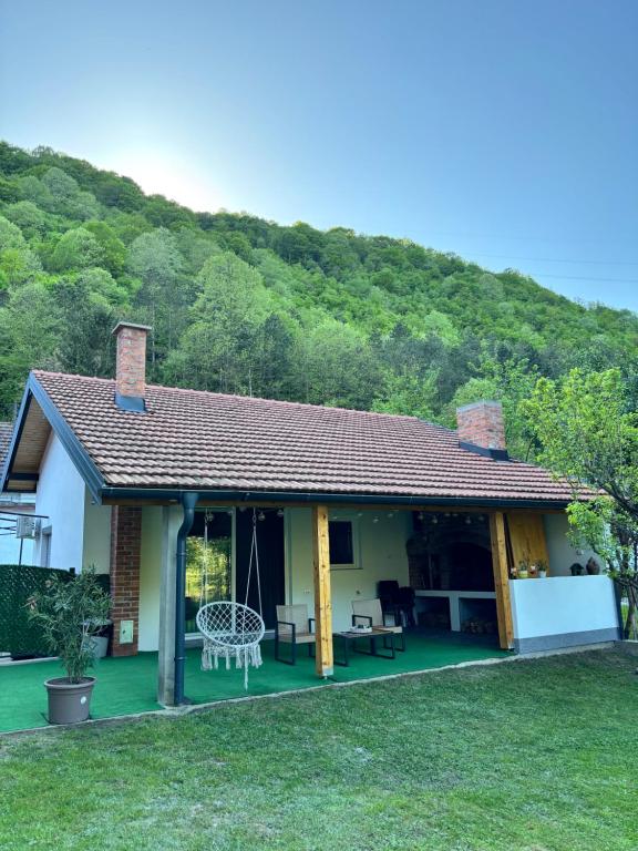 ein Haus mit einem grünen Hof mit einem Berg im Hintergrund in der Unterkunft Rivergreen in Banja Luka