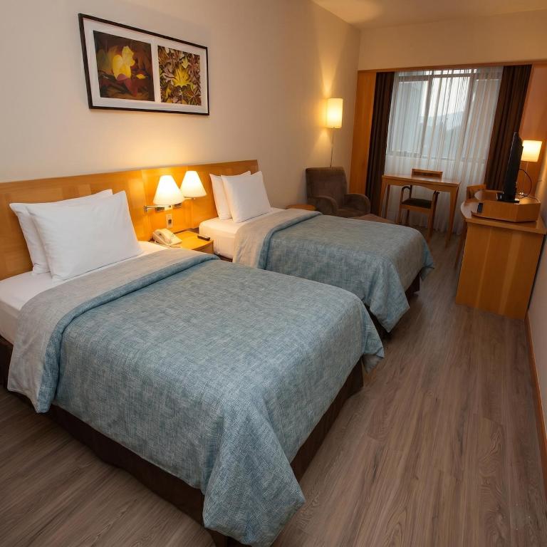 a hotel room with two beds and a chair at 807 - Hotel & Residence Sol Alphaville Flat in Barueri