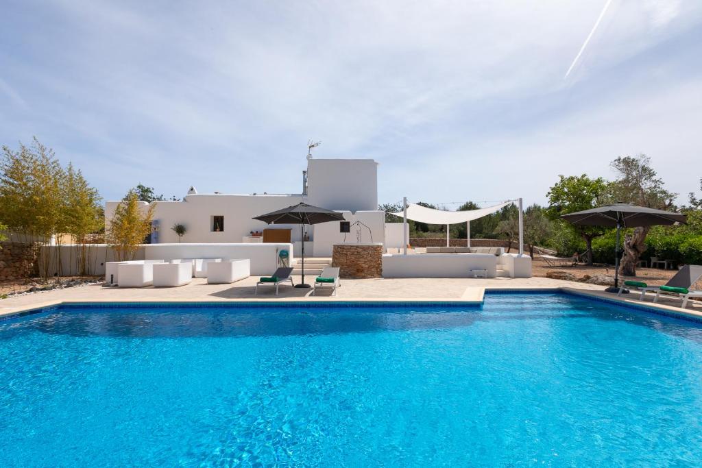 a large swimming pool with chairs and umbrellas at New! Villa Plana Menut in Santa Gertrudis de Fruitera