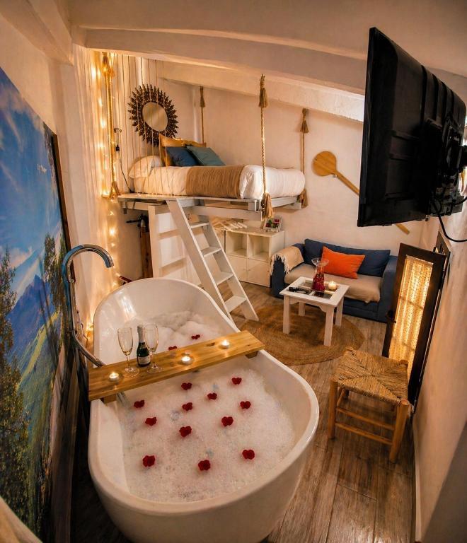 a bathroom with a bath tub and a bedroom at El Pitijopo in El Gastor