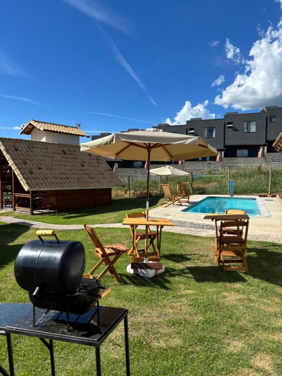 a backyard with a grill and tables and a pool at Chalés Champion Capitolio in Capitólio