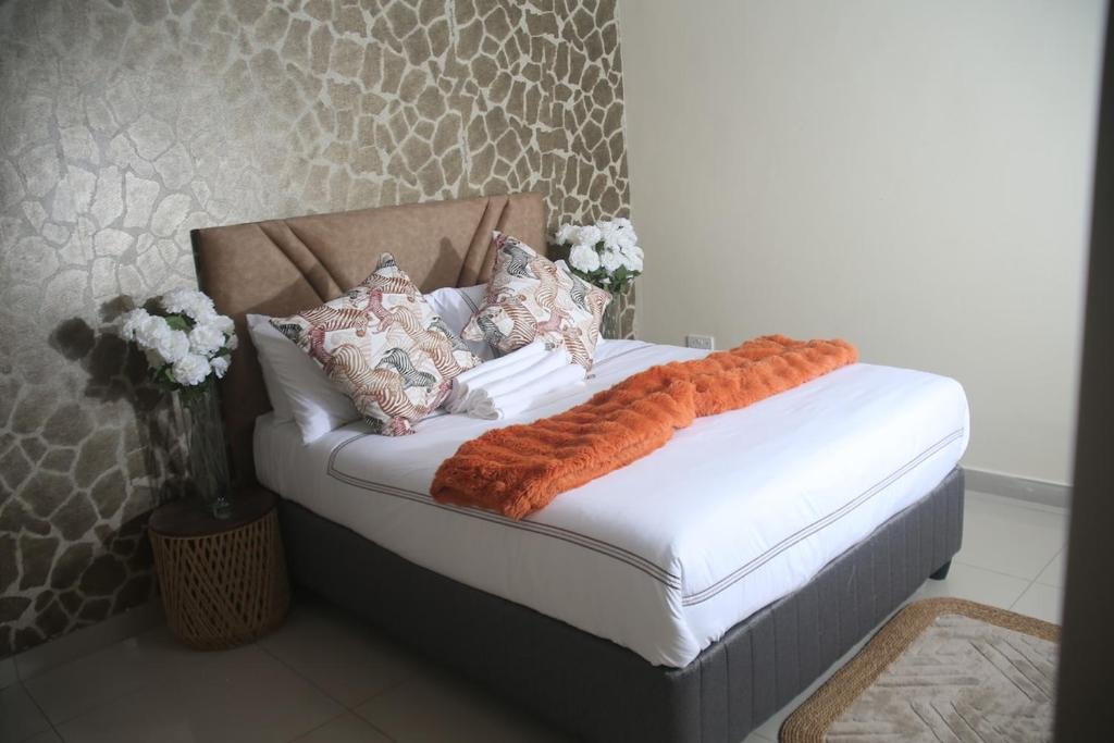 a bed with an orange blanket on it in a room at Maun Fortress in Maun Airport