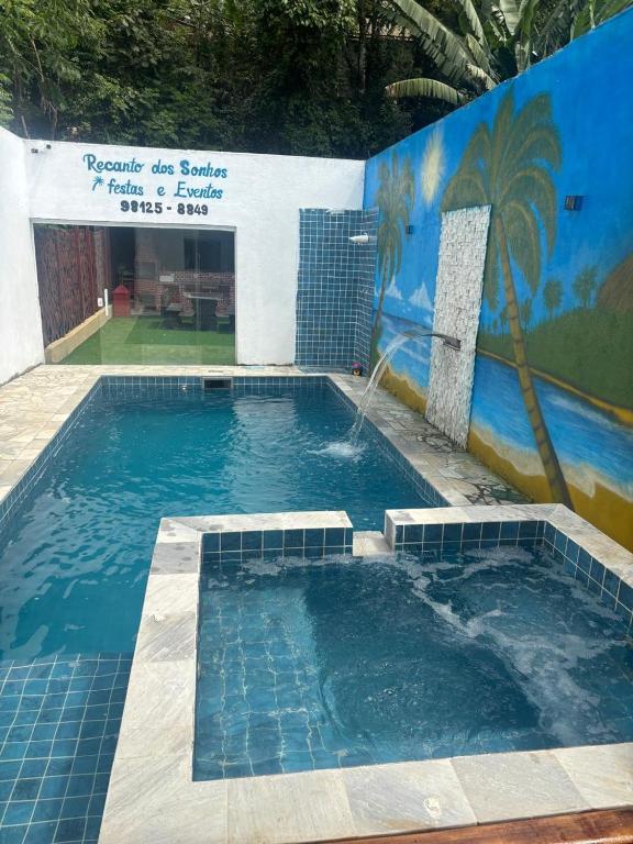 a swimming pool with a fountain in front of a wall at Espaço Recanto dos Sonhos DR in Itaquaquecetuba