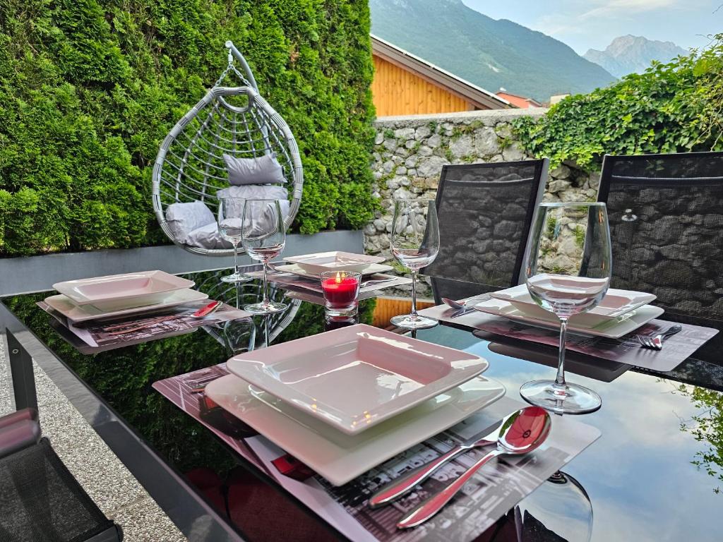 a table with plates and wine glasses on a patio at Sončna vila Bovec, Studio A&B in Bovec
