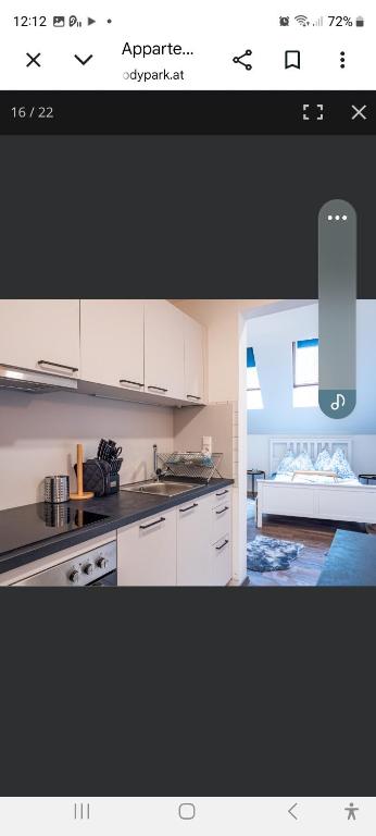 a kitchen with white cabinets and a room with a couch at Apartment Andras in Murau