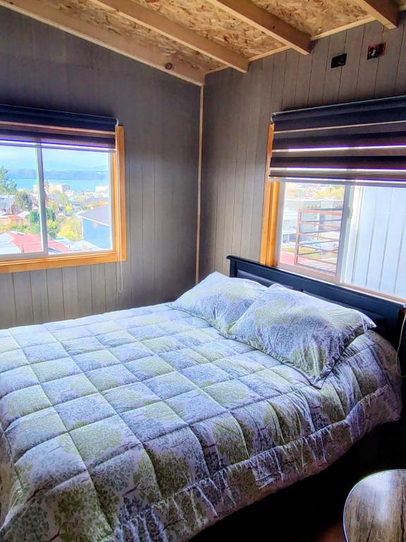 a bedroom with a bed and two windows at Casa kumey in Puerto Varas