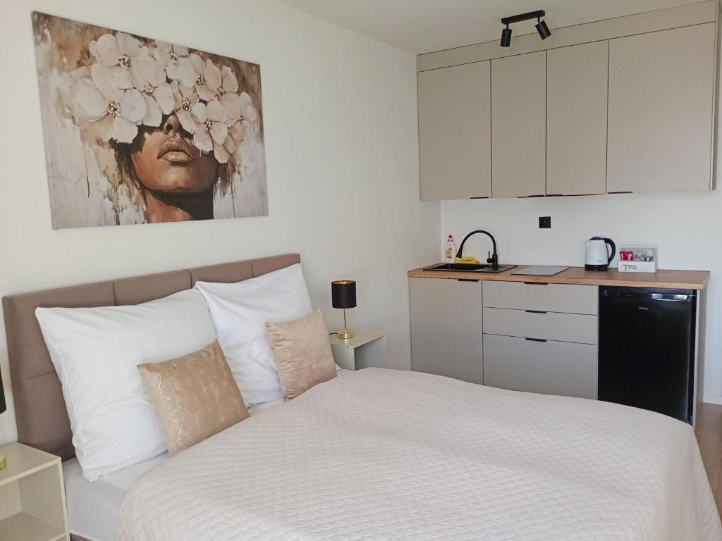 a bedroom with a white bed and a kitchen at Palomino pokoje agroturystyka in Świnoujście