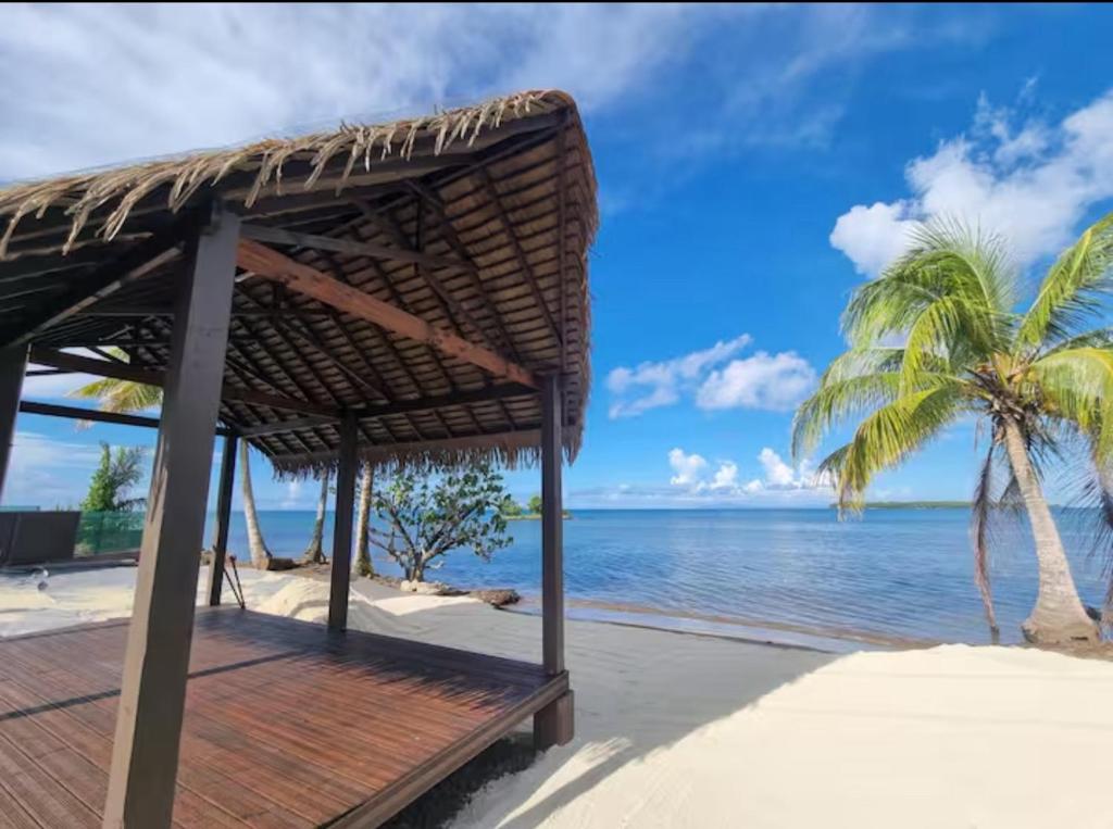a straw hut on the beach with a palm tree at Le Rainoa - Beach House in Taputapuapea