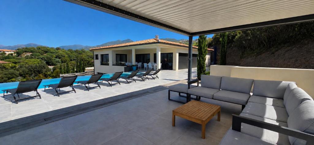 a patio with a couch and chairs and a pool at Villa Haut Standing Stella Di Mare vue panoramique in Propriano