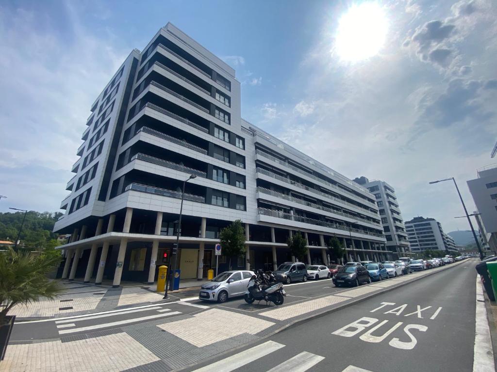 a large white building with cars parked in front of it at Donosti rooms in Loyola