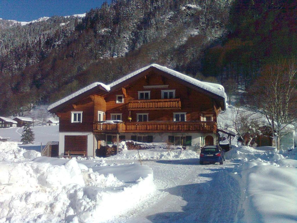 a house covered in snow in front of a mountain at Ferienwohnung Birgit in Sankt Gallenkirch