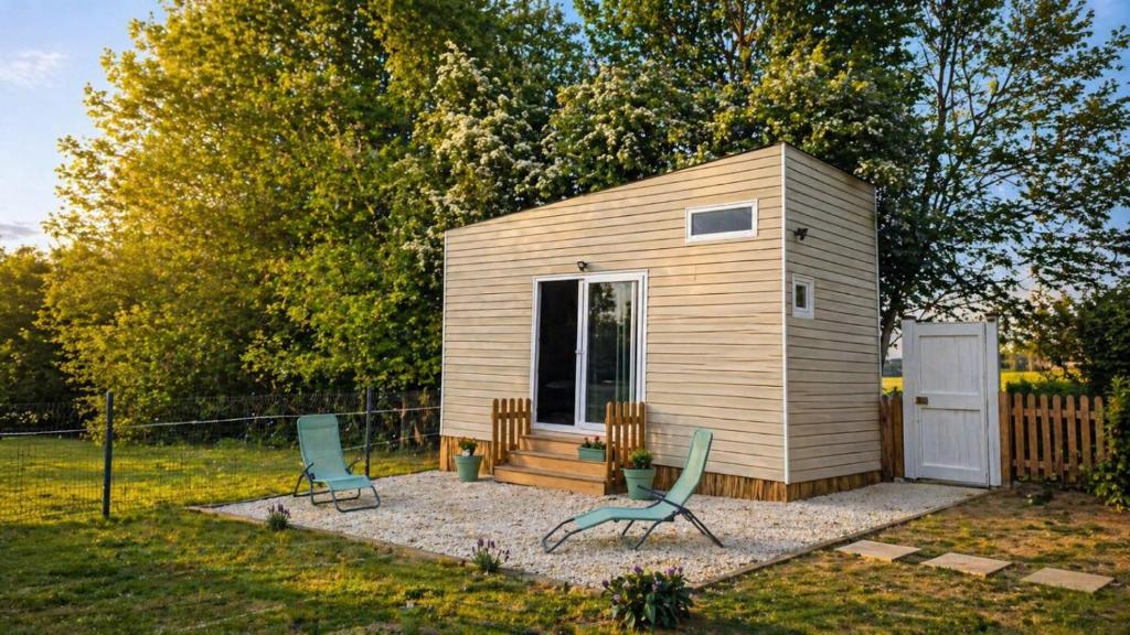 a tiny house with two chairs in a yard at Cabane insolite en pleine nature - La cabane de Dim in Grumesnil