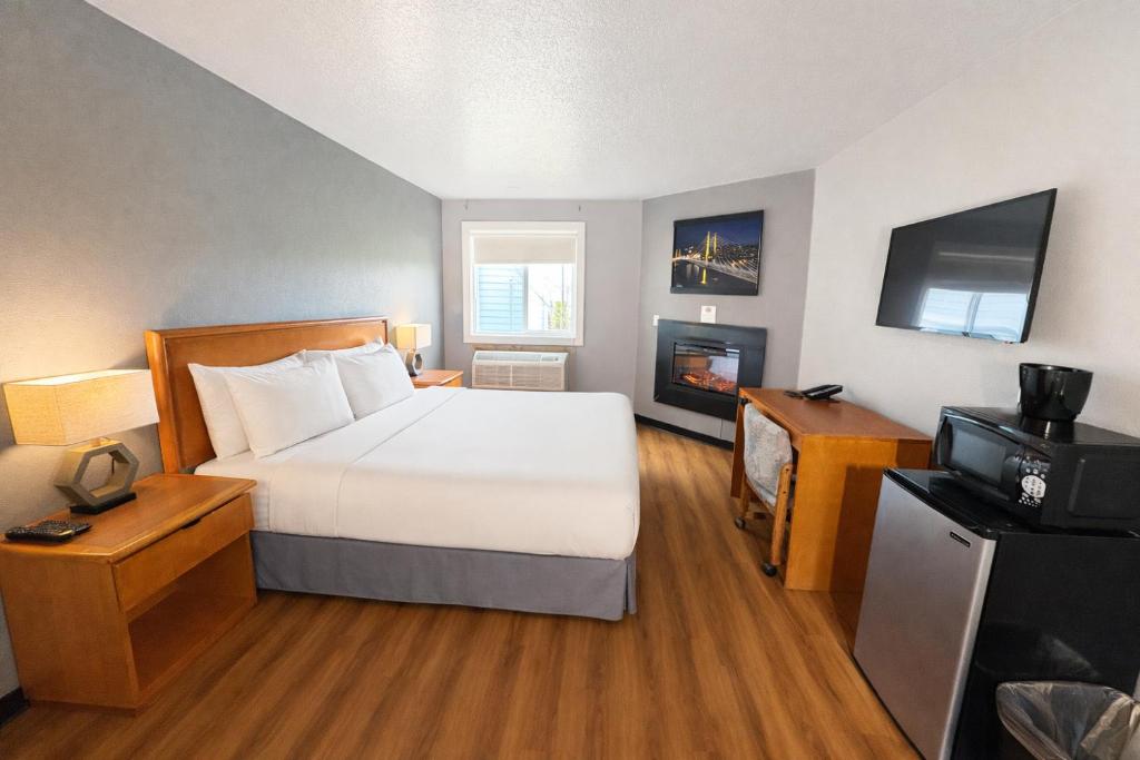 a hotel room with a bed and a television at Sunnyside Inn and Suites in Clackamas