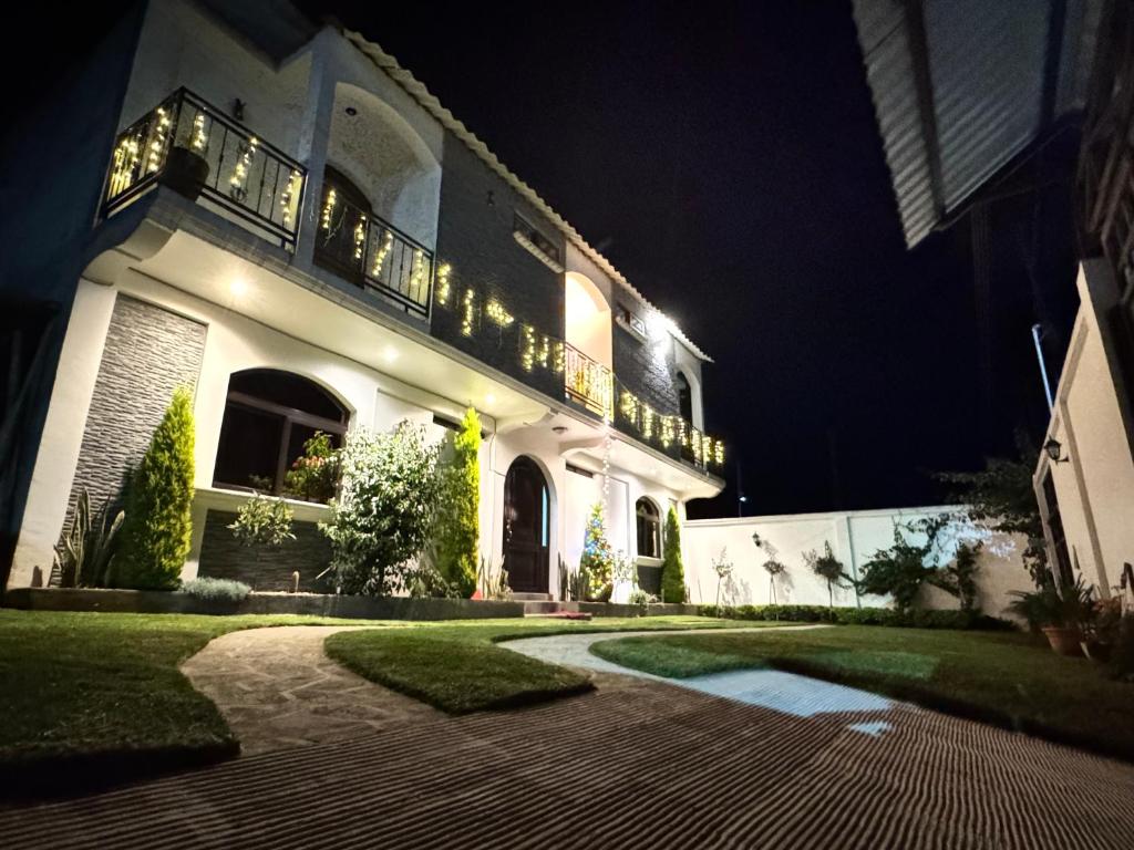 a large white house with a balcony at night at Hotel-cafetería TERRAVOLCAN in San Pedro Sacatepéquez