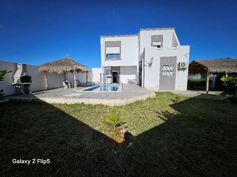 a large white house with a yard with a swimming pool at villa amani in Al Maqārisah