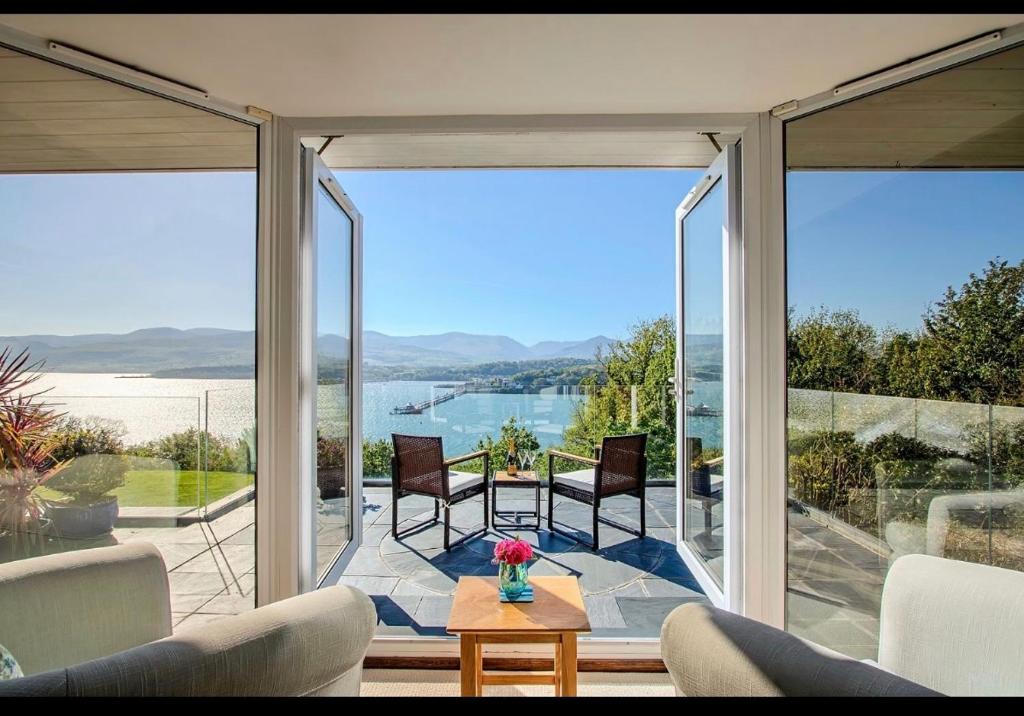 a living room with glass doors and a view of the water at Seascape at coed y berclas, luxury accommodation with stunning sea view in Llandegfan