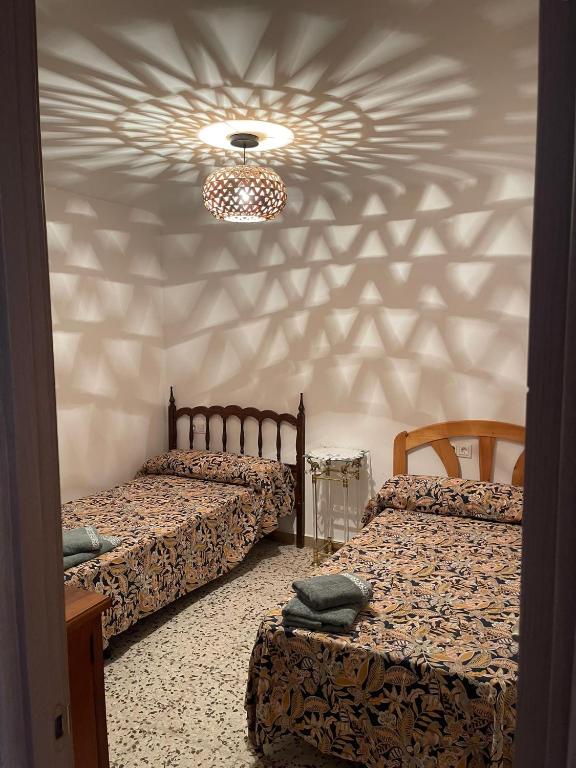 a bedroom with two beds and a chandelier at Antique villa in Guardamar del Segura