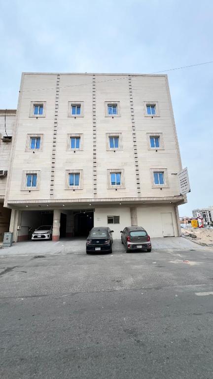 two cars parked in front of a large building at The Calm Suite in Al Khobar