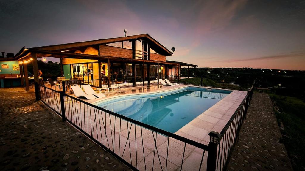 a house with a swimming pool in front of a house at Colores de Yacanto in Villa Yacanto